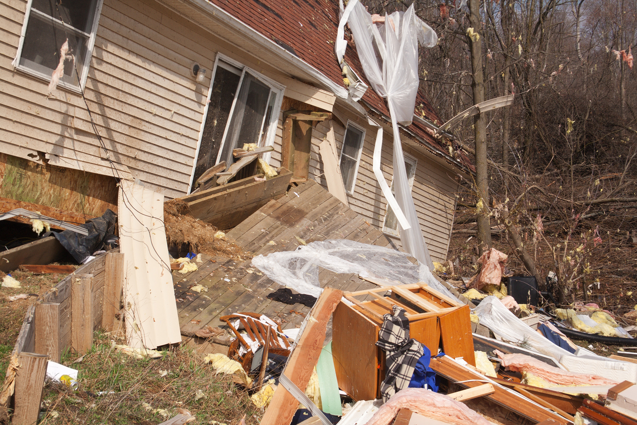 A storm-damaged Michigan home with debris in the front yard, requiring professional storm damage restoration.