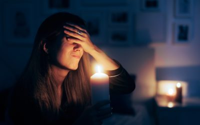 Woman holding up candle while struggling with the effects of a power outage in her home.