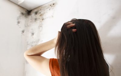 A woman holding her head in distress after finding mold in her Michigan home.